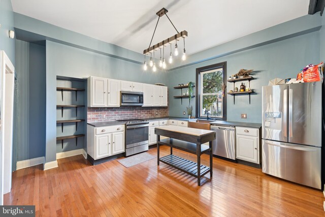 kitchen with white cabinets, pendant lighting, light wood-type flooring, and stainless steel appliances