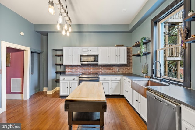 415 E Lafayette Ave, Baltimore, MD 21202 - kitchen featuring open shelves, appliances with stainless steel finishes, a sink, white cabinetry, and decorative backsplash
