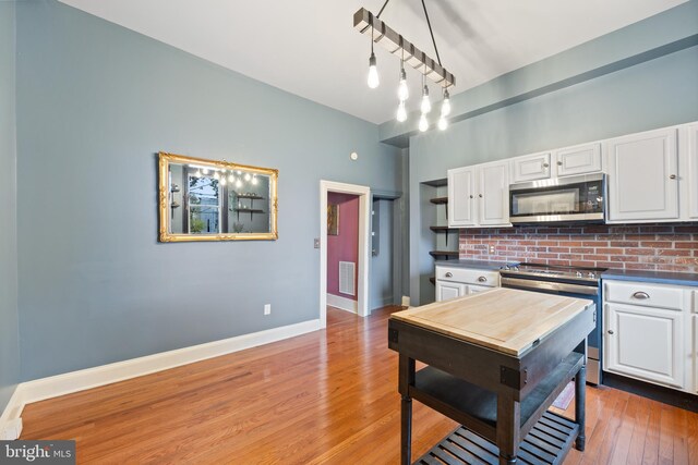 kitchen featuring white cabinets, appliances with stainless steel finishes, hardwood / wood-style flooring, and decorative backsplash