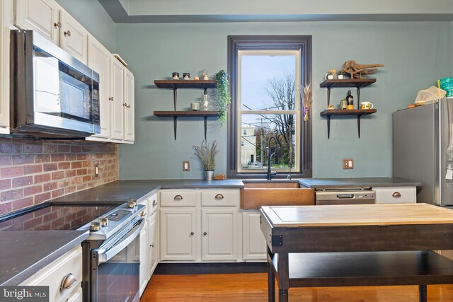 kitchen with hardwood / wood-style floors, appliances with stainless steel finishes, white cabinetry, and sink