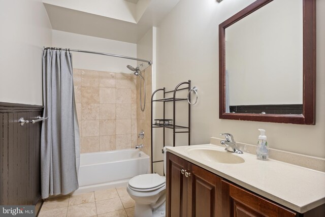 full bathroom with tile patterned floors, shower / bath combo with shower curtain, vanity, and toilet