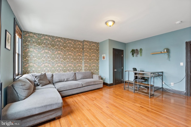415 E Lafayette Ave, Baltimore, MD 21202 - living area featuring an accent wall, wallpapered walls, wood finished floors, a desk, and baseboards