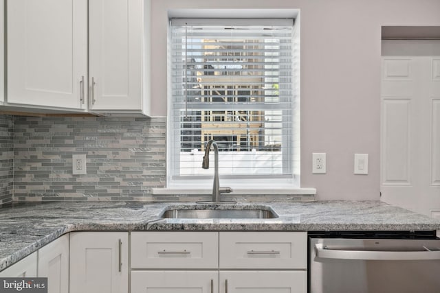 kitchen featuring sink, dishwasher, white cabinetry, backsplash, and light stone countertops