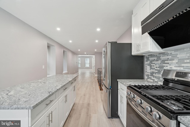 kitchen featuring white cabinetry, stainless steel gas range oven, extractor fan, and decorative backsplash