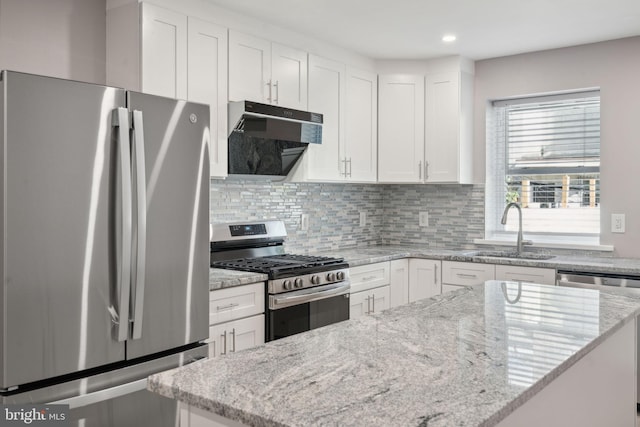 kitchen featuring sink, stainless steel appliances, light stone countertops, white cabinets, and decorative backsplash