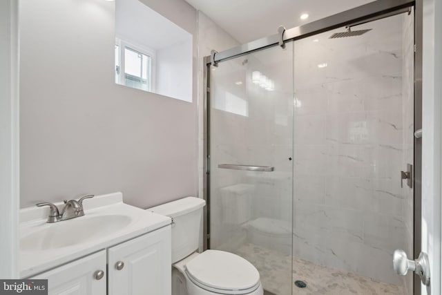 bathroom featuring vanity, toilet, and a shower with door