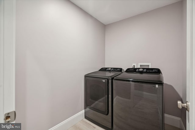 washroom with light hardwood / wood-style floors and washing machine and clothes dryer