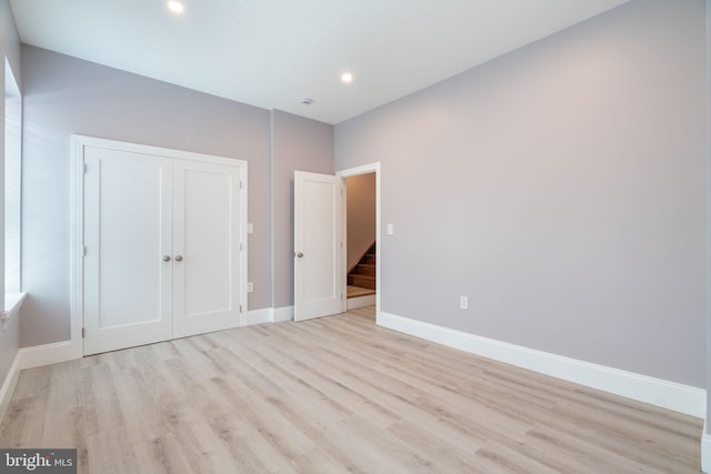 unfurnished bedroom with light hardwood / wood-style floors and a closet