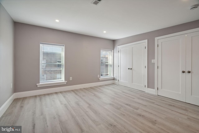 unfurnished bedroom with two closets and light wood-type flooring