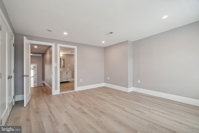 unfurnished bedroom with connected bathroom and light wood-type flooring