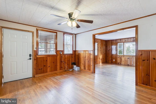 foyer featuring ceiling fan, crown molding, wooden walls, and light hardwood / wood-style flooring