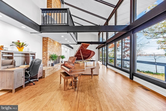 miscellaneous room with a water view, beamed ceiling, high vaulted ceiling, and light wood-type flooring