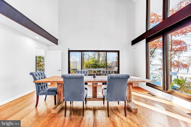 dining area with plenty of natural light, a towering ceiling, and light hardwood / wood-style floors