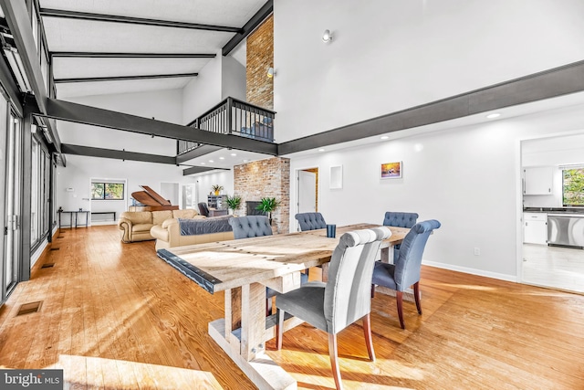 dining space featuring light hardwood / wood-style floors, beam ceiling, and a brick fireplace