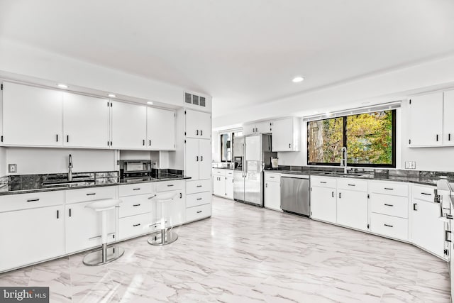 kitchen with white cabinets, sink, appliances with stainless steel finishes, and dark stone counters