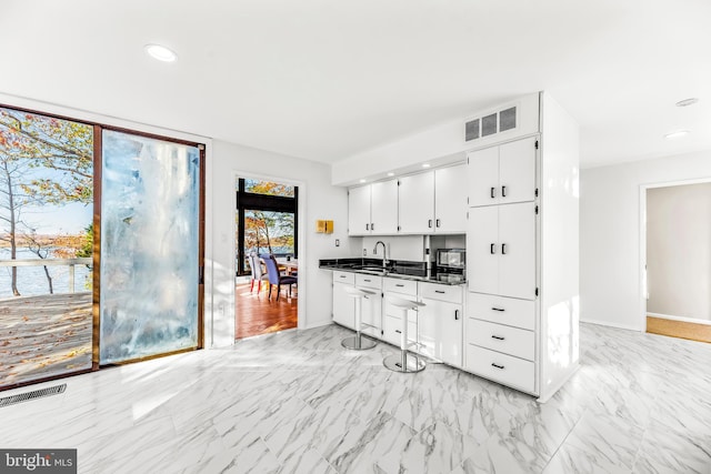 kitchen with white cabinets, a water view, and sink