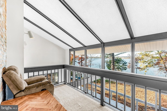 sunroom / solarium featuring a water view and lofted ceiling with beams