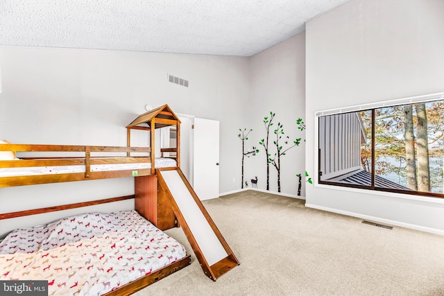 carpeted bedroom featuring a textured ceiling and high vaulted ceiling