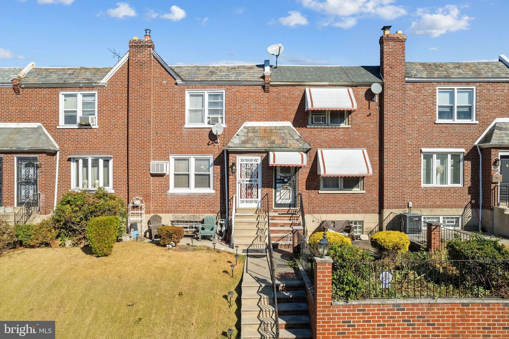 view of front of home with an AC wall unit, cooling unit, and a front yard