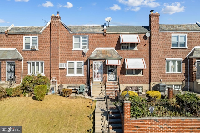 view of front of home with an AC wall unit, cooling unit, and a front yard