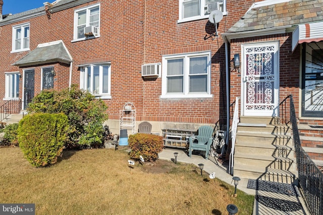 exterior space featuring a wall mounted air conditioner and a front lawn