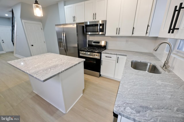 kitchen featuring stainless steel appliances, white cabinetry, pendant lighting, sink, and a center island