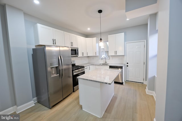 kitchen with light hardwood / wood-style flooring, a kitchen island, pendant lighting, appliances with stainless steel finishes, and white cabinetry