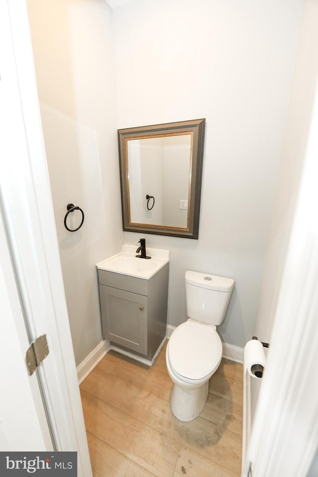 bathroom with wood-type flooring, toilet, and vanity