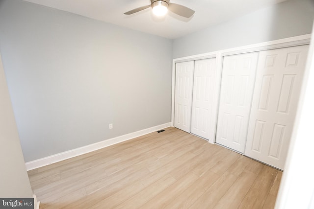 unfurnished bedroom featuring multiple closets, light wood-type flooring, and ceiling fan