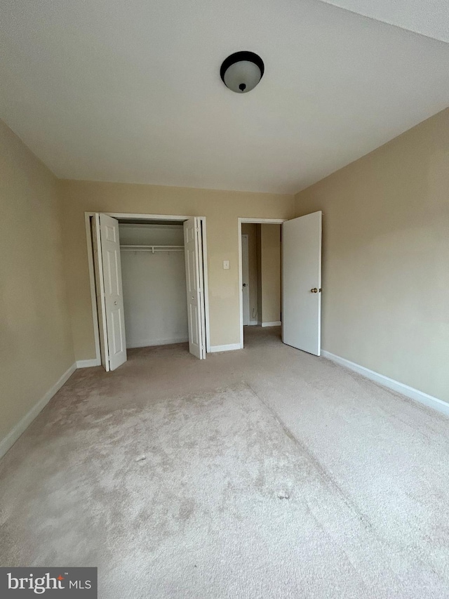 unfurnished bedroom with light carpet and a closet