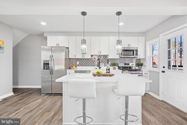 kitchen with white cabinetry, decorative light fixtures, and stainless steel appliances