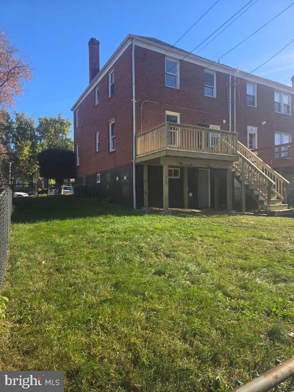 rear view of house featuring a deck and a lawn