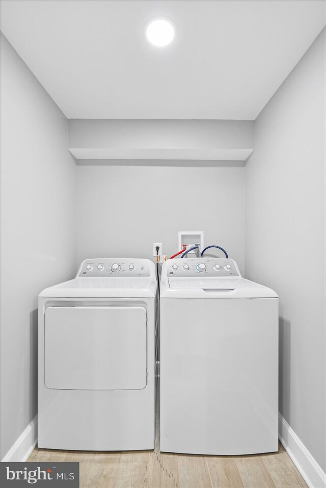 clothes washing area featuring hardwood / wood-style flooring and washer and dryer