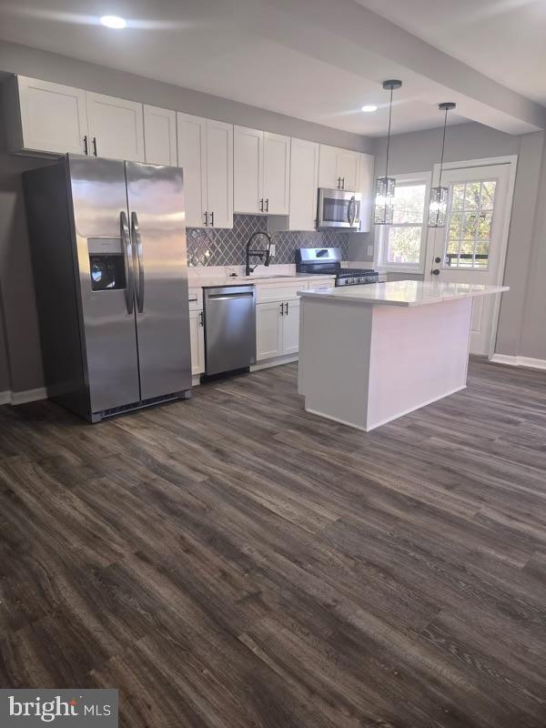 kitchen featuring white cabinetry, appliances with stainless steel finishes, decorative light fixtures, and dark hardwood / wood-style flooring