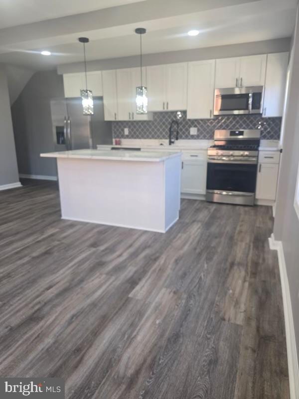 kitchen featuring white cabinetry, a center island, hanging light fixtures, dark hardwood / wood-style floors, and stainless steel appliances