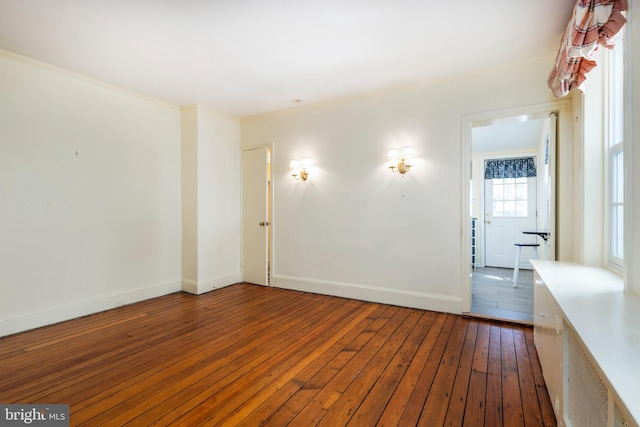 spare room featuring dark wood-type flooring and crown molding