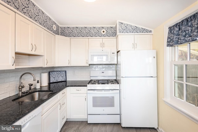 kitchen featuring white cabinets, sink, lofted ceiling, dark stone counters, and white appliances