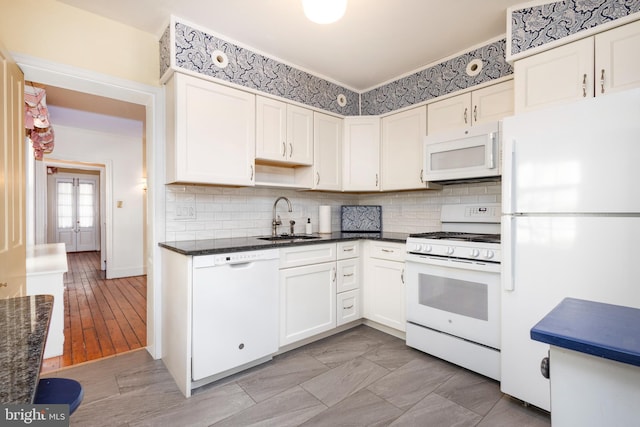 kitchen featuring white cabinetry, sink, dark stone countertops, white appliances, and light wood-type flooring