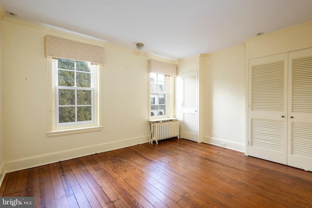 unfurnished bedroom featuring radiator heating unit, multiple windows, ornamental molding, and hardwood / wood-style floors