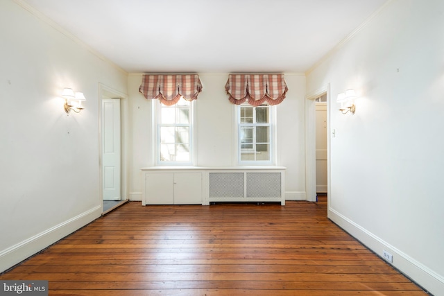 empty room featuring radiator, crown molding, and wood-type flooring