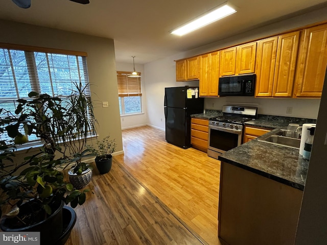 kitchen with ceiling fan, sink, hanging light fixtures, black appliances, and light wood-type flooring