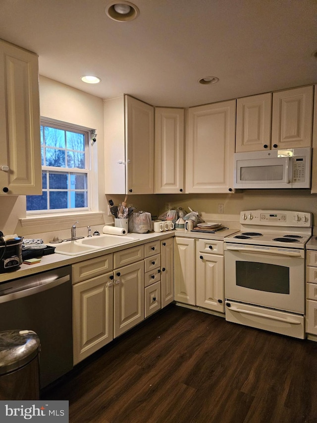 kitchen with dark wood-type flooring, white appliances, and sink