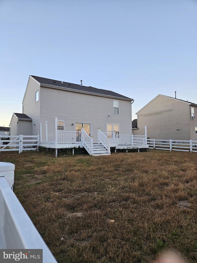 rear view of property featuring a lawn and a wooden deck