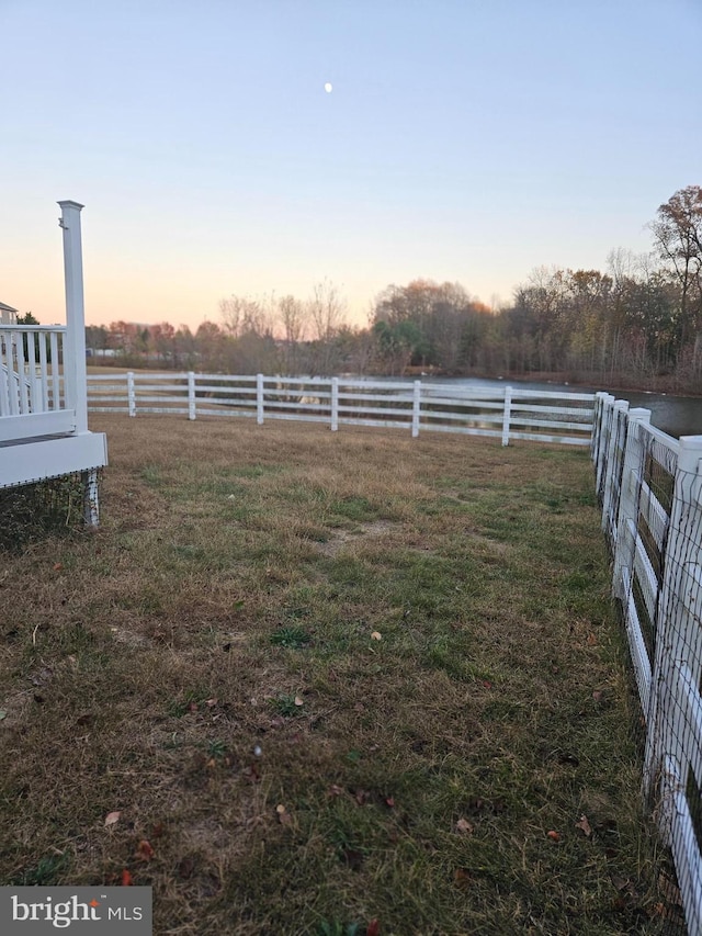 yard at dusk featuring a rural view and a water view