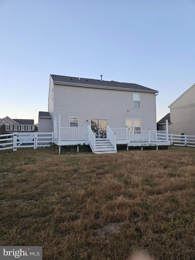 back of house with a wooden deck and a lawn