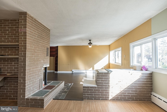 interior space featuring hardwood / wood-style floors, ceiling fan, a brick fireplace, and a baseboard radiator