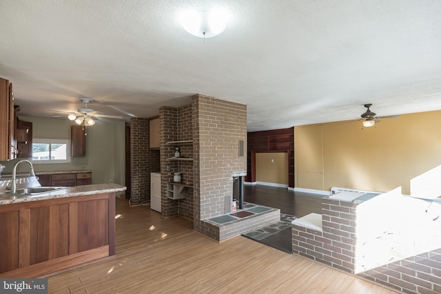 kitchen with kitchen peninsula, a textured ceiling, ceiling fan, sink, and hardwood / wood-style floors