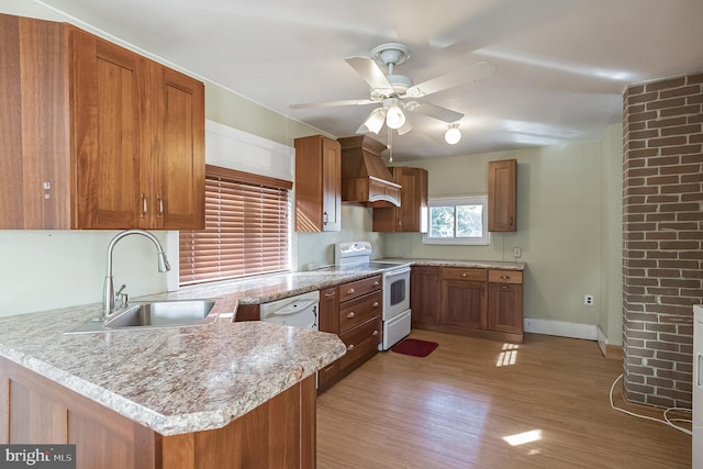 kitchen with white appliances, sink, ceiling fan, light hardwood / wood-style floors, and kitchen peninsula