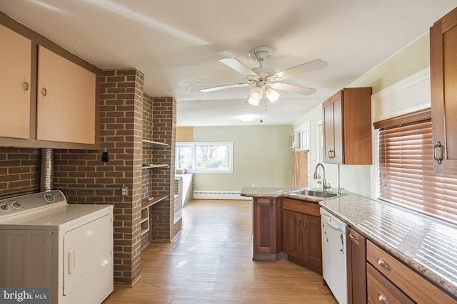 kitchen featuring sink, white dishwasher, light hardwood / wood-style flooring, and washer / dryer