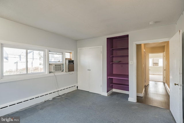 unfurnished bedroom with dark colored carpet, a closet, and baseboard heating